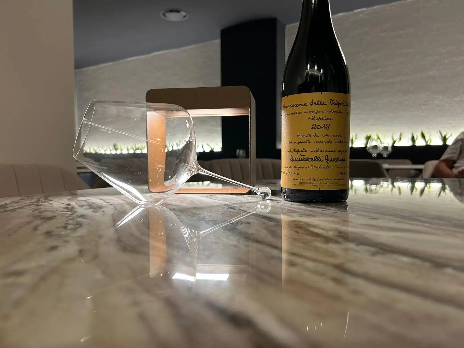 Bottiglia di Amarone su tavolo di marmo con calice rovesciato